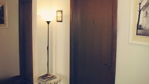 A hallway with a wooden door, a table with a lace tablecloth, and a chandelier. - Holiday Sunny Roma B&B (Rome)