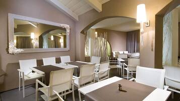 Une chambre d’hôtel avec un grand miroir, des chaises blanches, une table à manger et une lampe.