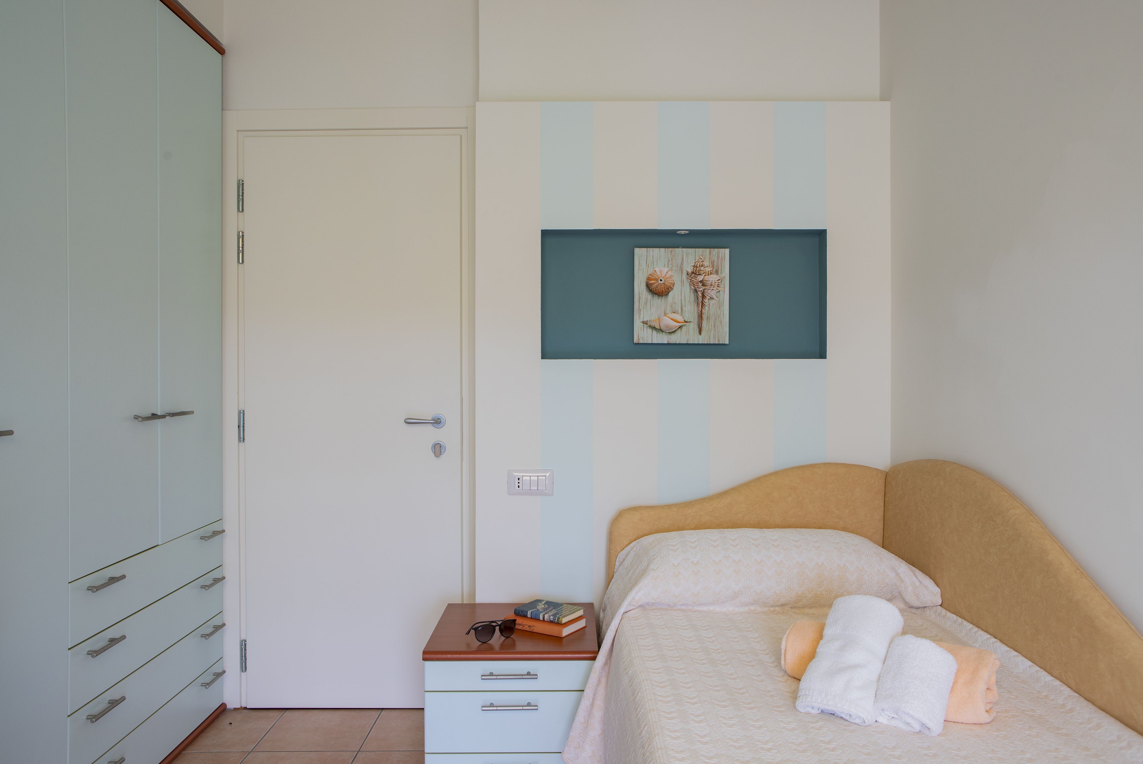 A bedroom with a bed, a nightstand, a wardrobe, and a wall-mounted picture.
