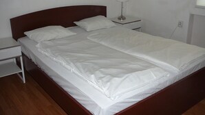 A neatly made bed in a room with a wooden headboard and a bedside table with a lamp.