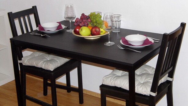 A dining table set with a fruit bowl, wine glasses, and cutlery.