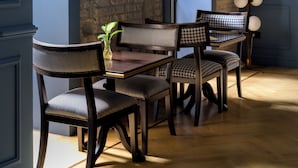 A dining area with a brick wall, wooden chairs, a table, and a framed picture on the wall. - The Fifteen Keys Hotel (Rome)