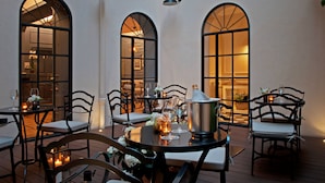 An outdoor dining area with tables and chairs, arched windows, and ambient lighting. - The Fifteen Keys Hotel (Rome)