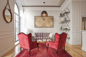 Un salon avec un canapé rouge, deux fauteuils rouges, une table basse et une grande carte du monde accrochée au mur.