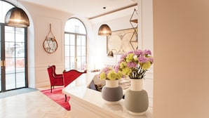 A modern hotel lobby with a large arched window, red chairs, and two vases with flowers on a counter. - The Fifteen Keys Hotel (Rome)