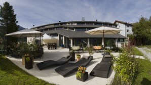 Um hotel moderno com área externa, varanda coberta e vista para as montanhas.