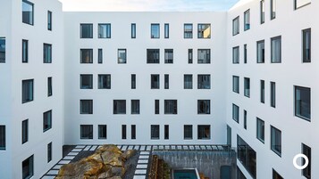 Un edificio moderno con un patio que incluye un jardín de rocas y una piscina.