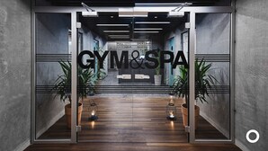 A modern interior with a reception desk labeled "GYM&SPA" and a wooden floor.