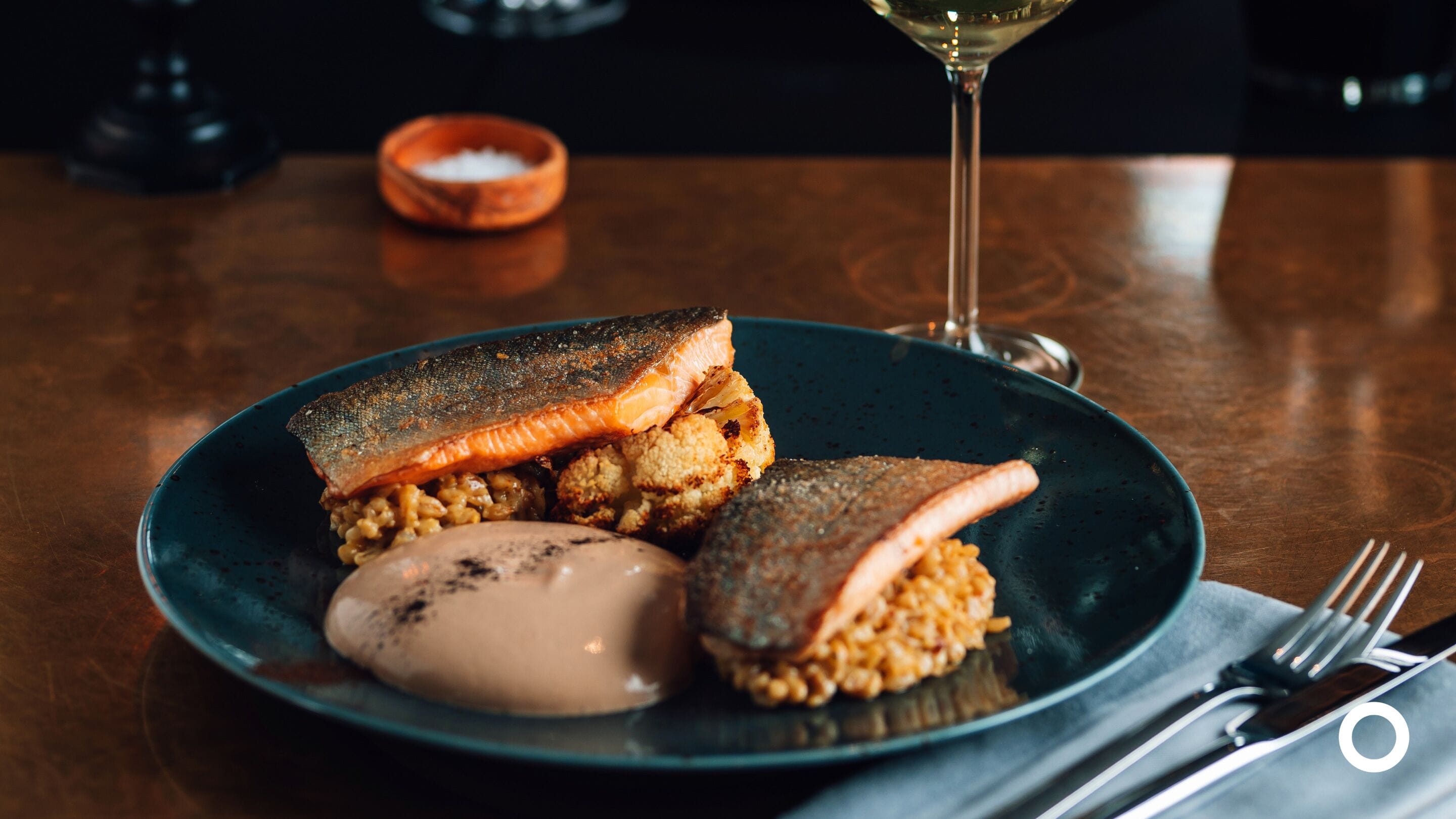 A plate with salmon, rice, and a dessert on a dark plate.