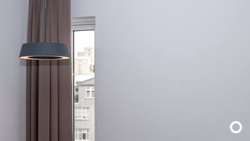 A modern room with a large window, a vertical light fixture, and a view of buildings outside.