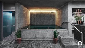A modern indoor pool with a concrete interior, two potted plants, and a staircase leading to a higher level. - Miðgarður by Center Hotels (Reykjavik)