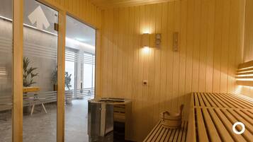 A wooden interior with a bench, a small table, and a wall-mounted heater.