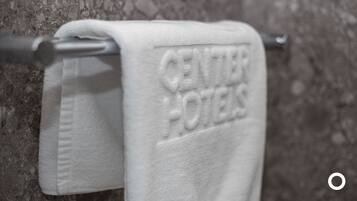 A white towel with "CENTURY HOTELS" embossed on it, hanging on a metal towel bar.
