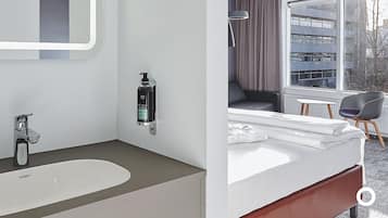 Un baño moderno con un lavamanos grande, un espejo y una botella de jabón para manos.