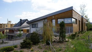 Een modern huis met twee verdiepingen, een schuin dak, grote ramen en een houten gevel.