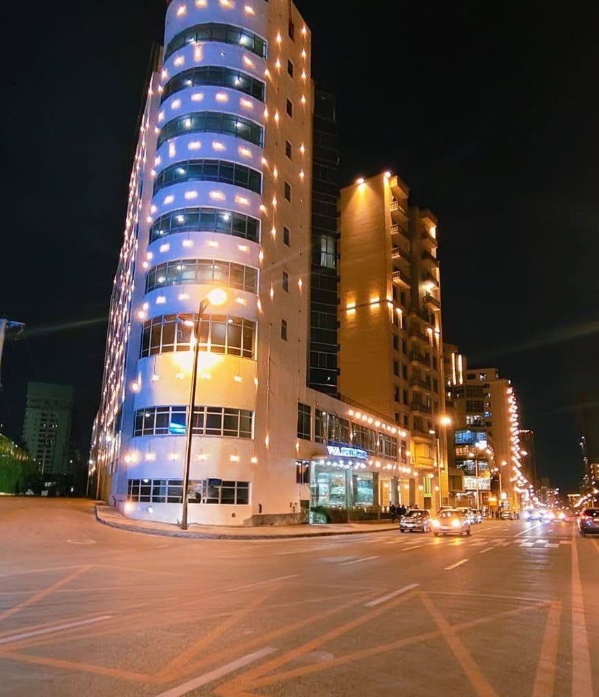 Un immeuble à plusieurs étages, doté de fenêtres illuminées et d’une façade incurvée.