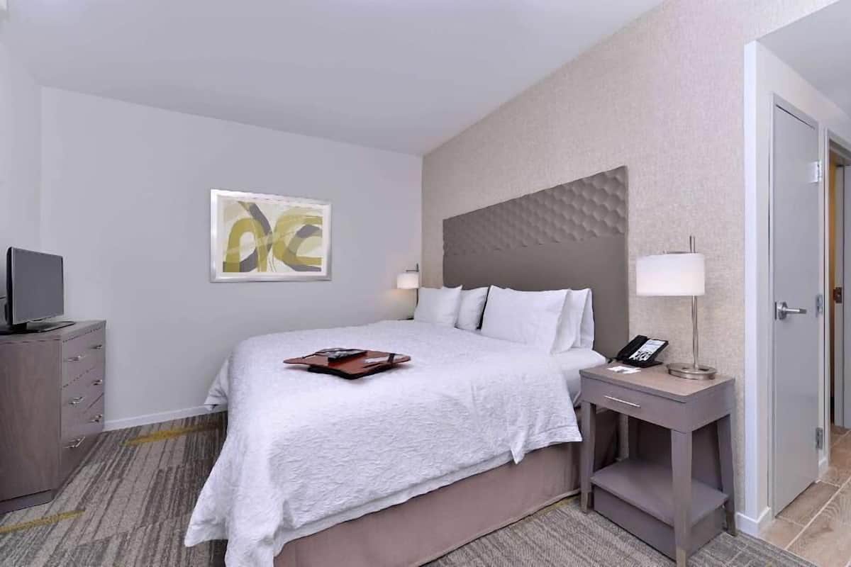 Une chambre d’hôtel avec un lit, une table de chevet, une lampe et un tableau au mur.