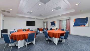A conference room with round tables, blue chairs, and orange tablecloths.
