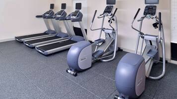 Een fitnessruimte met loopbanden, crosstrainers en een stair climber.