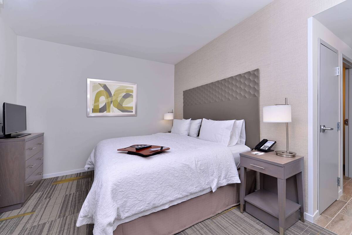 Une chambre d’hôtel avec un lit, une table de chevet, une lampe et un tableau au mur.