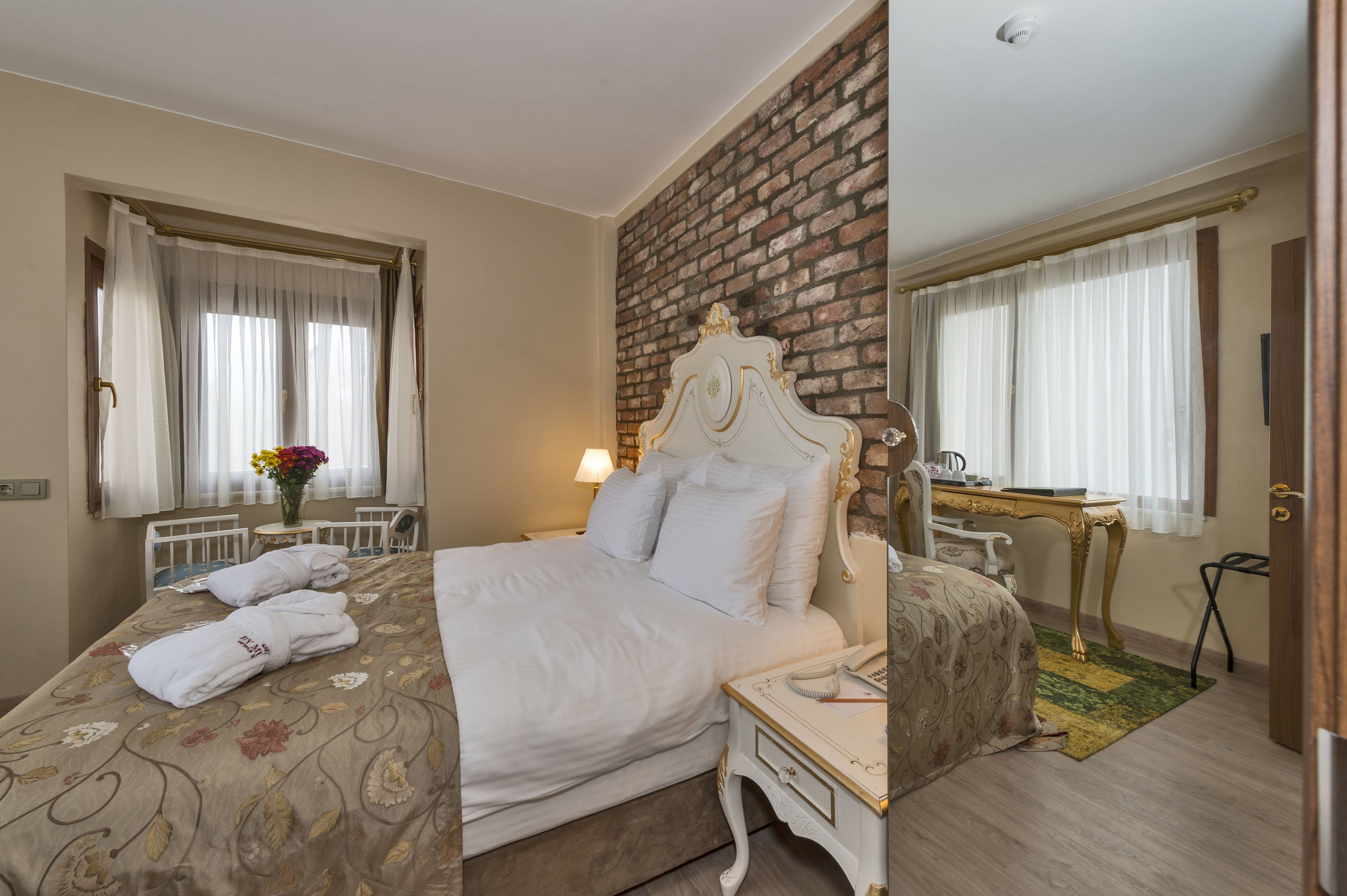 A hotel room with a large bed, a desk, and a mirror.