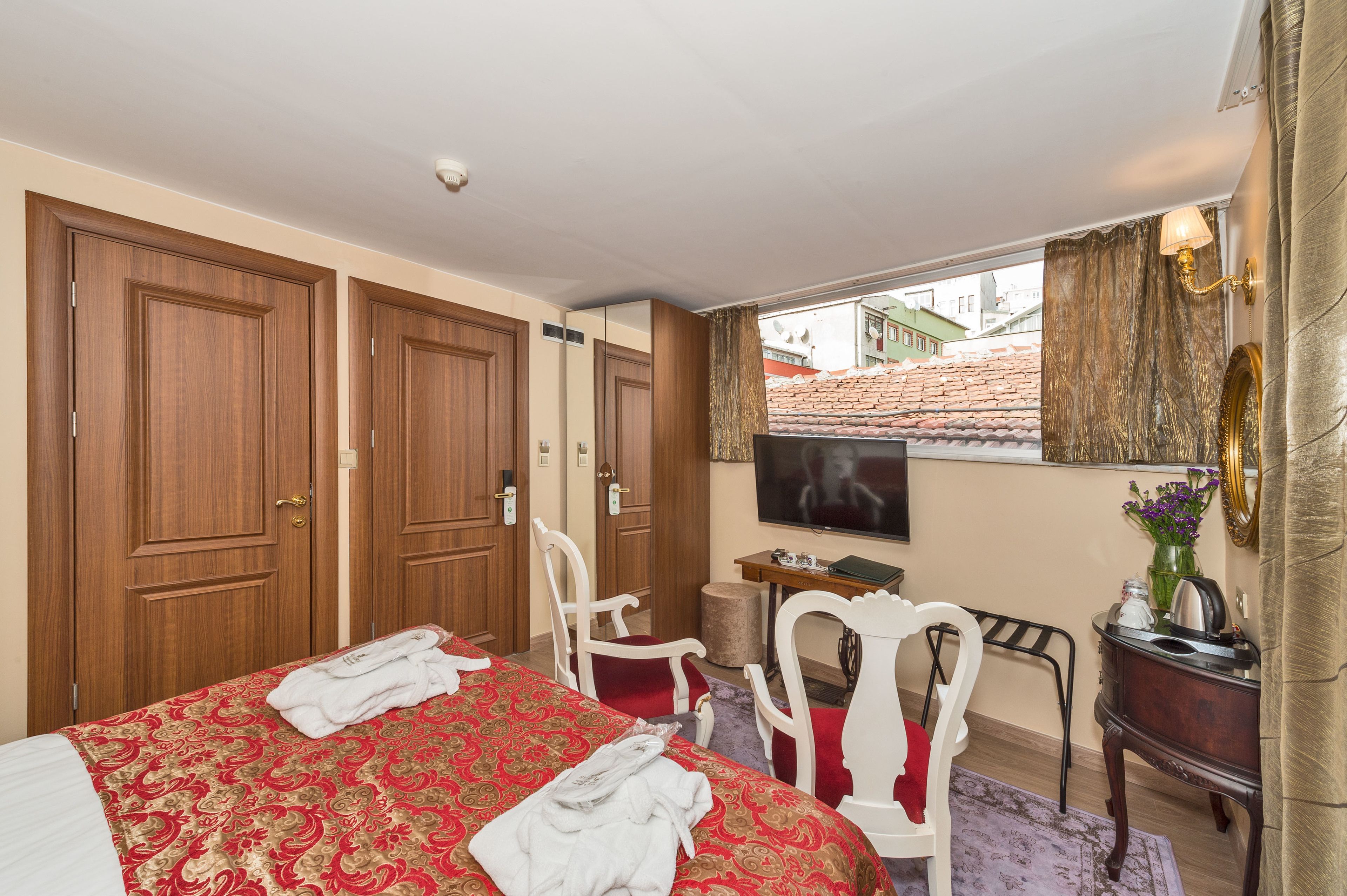 Une chambre d’hôtel avec un grand lit, une armoire en bois, une télévision, un bureau et une vue sur les bâtiments environnants.