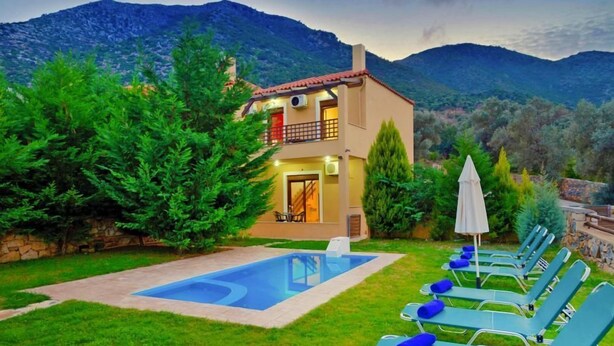 Ein zweistöckiges Haus mit Swimmingpool und Liegestühlen.