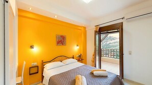 Ein Hotelzimmer mit Bett, Sessel, Nachttisch und Blick ins Freie.