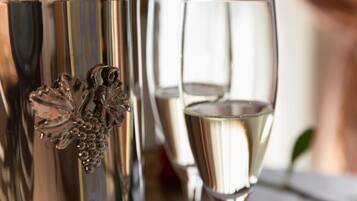 Een close-up van een metalen container met een decoratieve handgreep en een glas gevuld met een heldere vloeistof, waarschijnlijk een drankje.