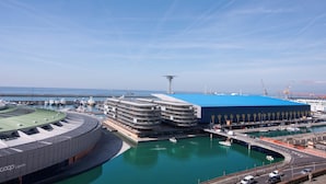 Un puerto deportivo con barcos, un edificio azul grande y una estructura circular.