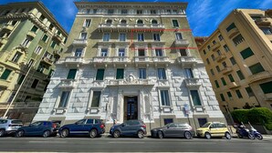Un edificio de varios pisos con arquitectura clásica, que presenta una entrada central con una puerta y ventanas en cada nivel.