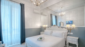 Una habitación de hotel con una cama grande, un candelabro, un espejo y un televisor.