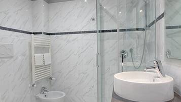 A modern bathroom with a glass-enclosed shower, a round sink, and a toilet.