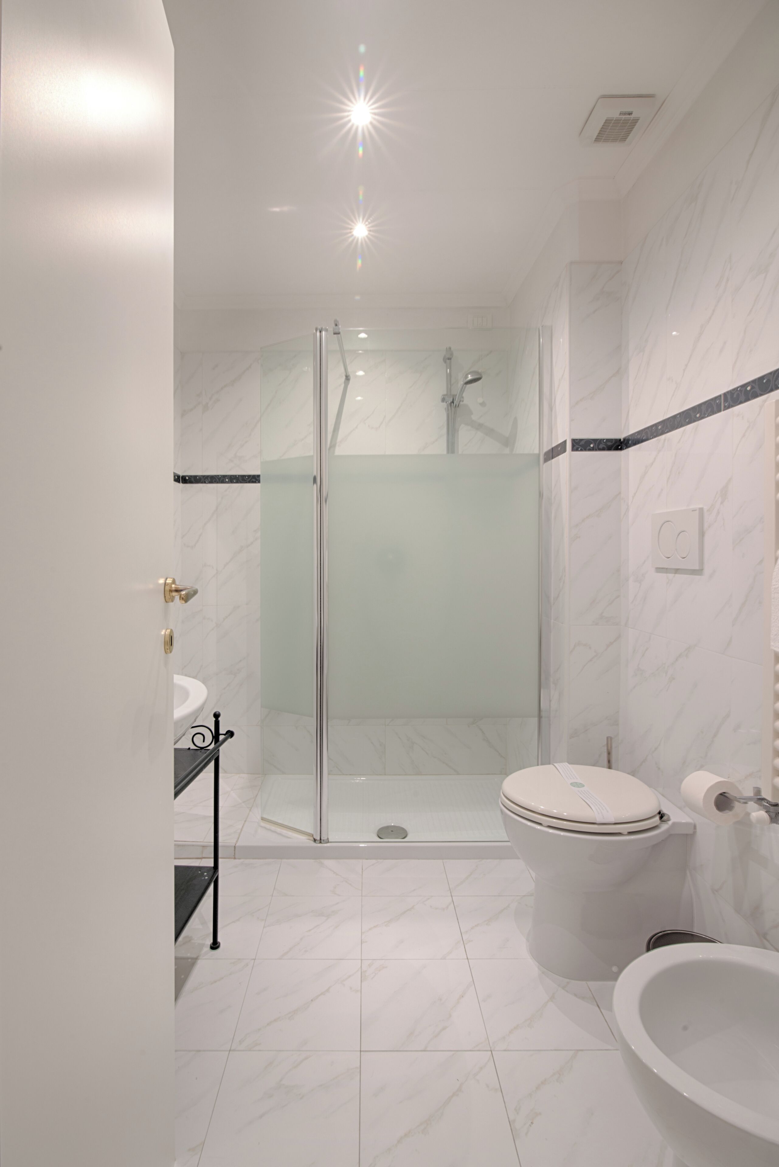 Un bagno moderno con cabina doccia in vetro, vaso sospeso bianco, lavabo e vasca da bagno.