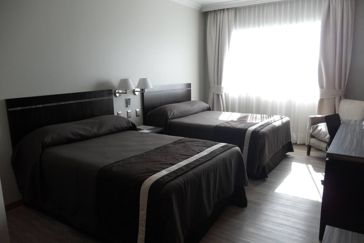 Habitació d'hotel amb dos llits, un escriptori i una cadira.