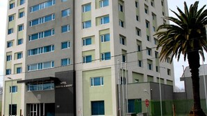 Um hotel de vários andares com design moderno, destacando uma fachada plana e inúmeras janelas.