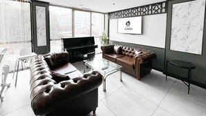 A modern living room with a leather sofa, a glass coffee table, and a flat-screen TV. - Aldino Hotel & Spa (Ankara)