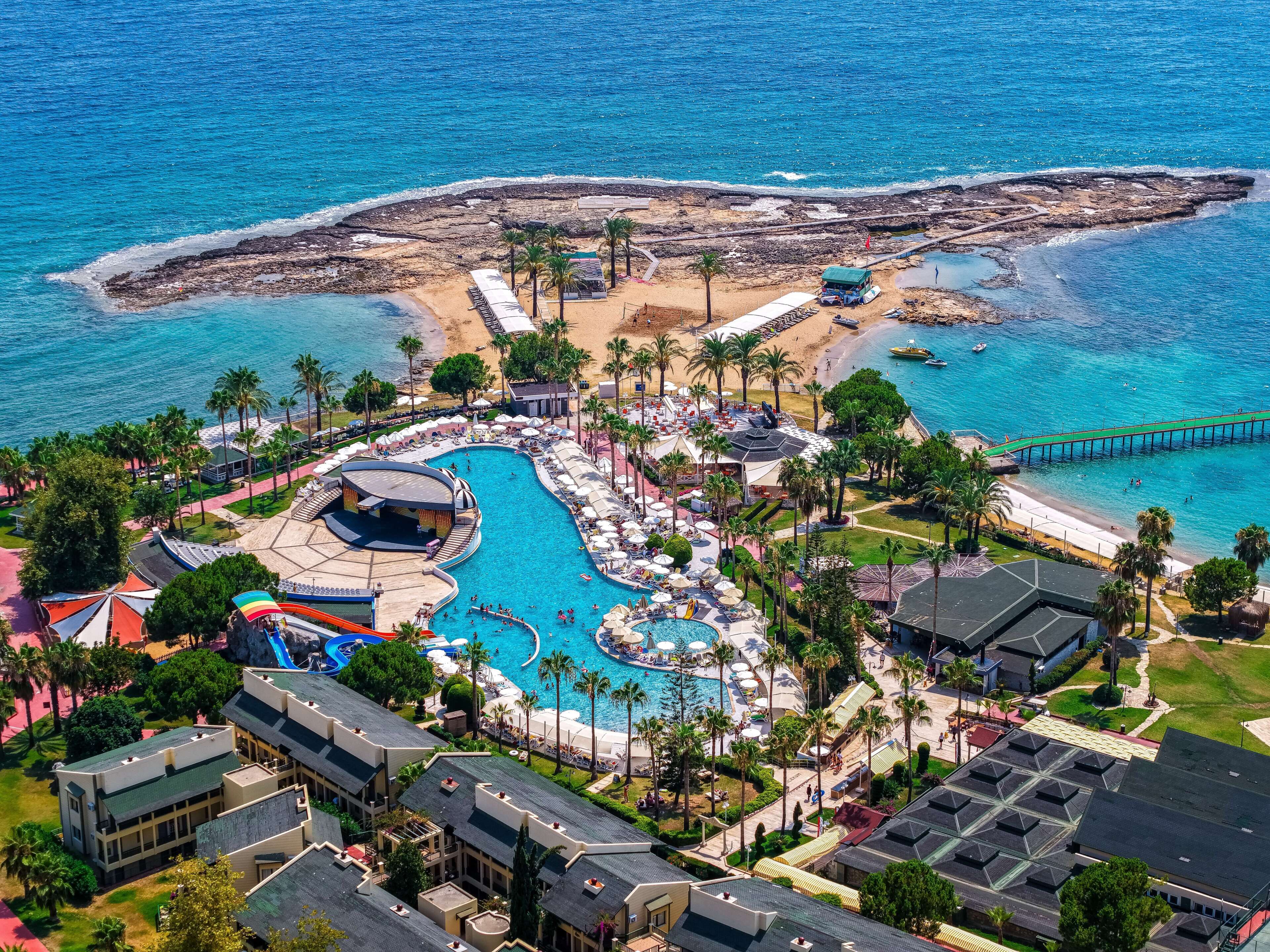 Um resort com uma piscina grande, acesso à praia e um píer.