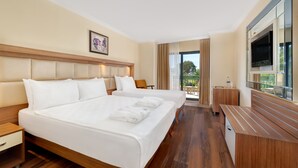 Habitación de hotel con dos camas, televisión, escritorio y balcón con vistas.