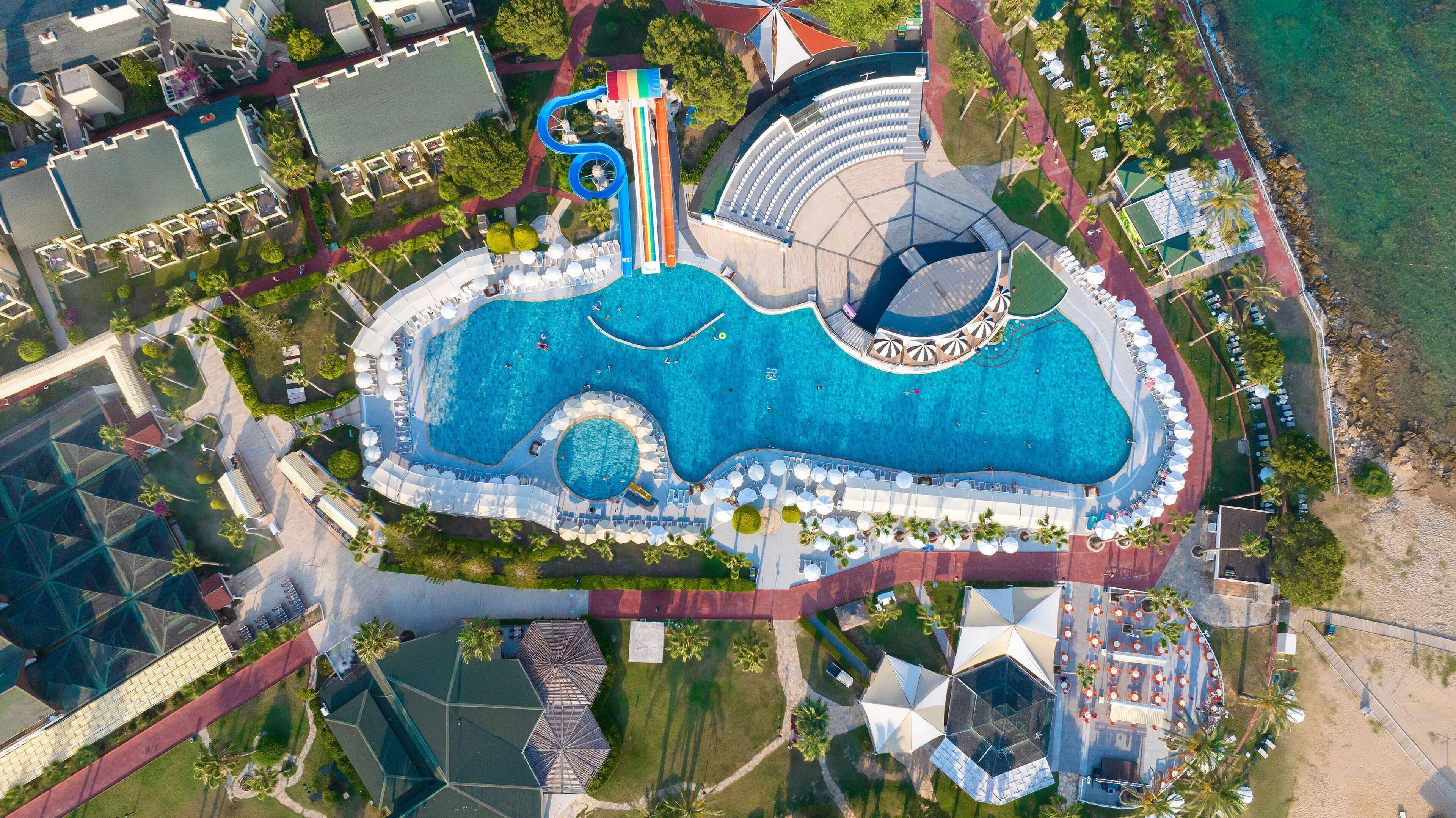 Vista aérea de um resort com uma piscina grande, um tobogã e um edifício circular.