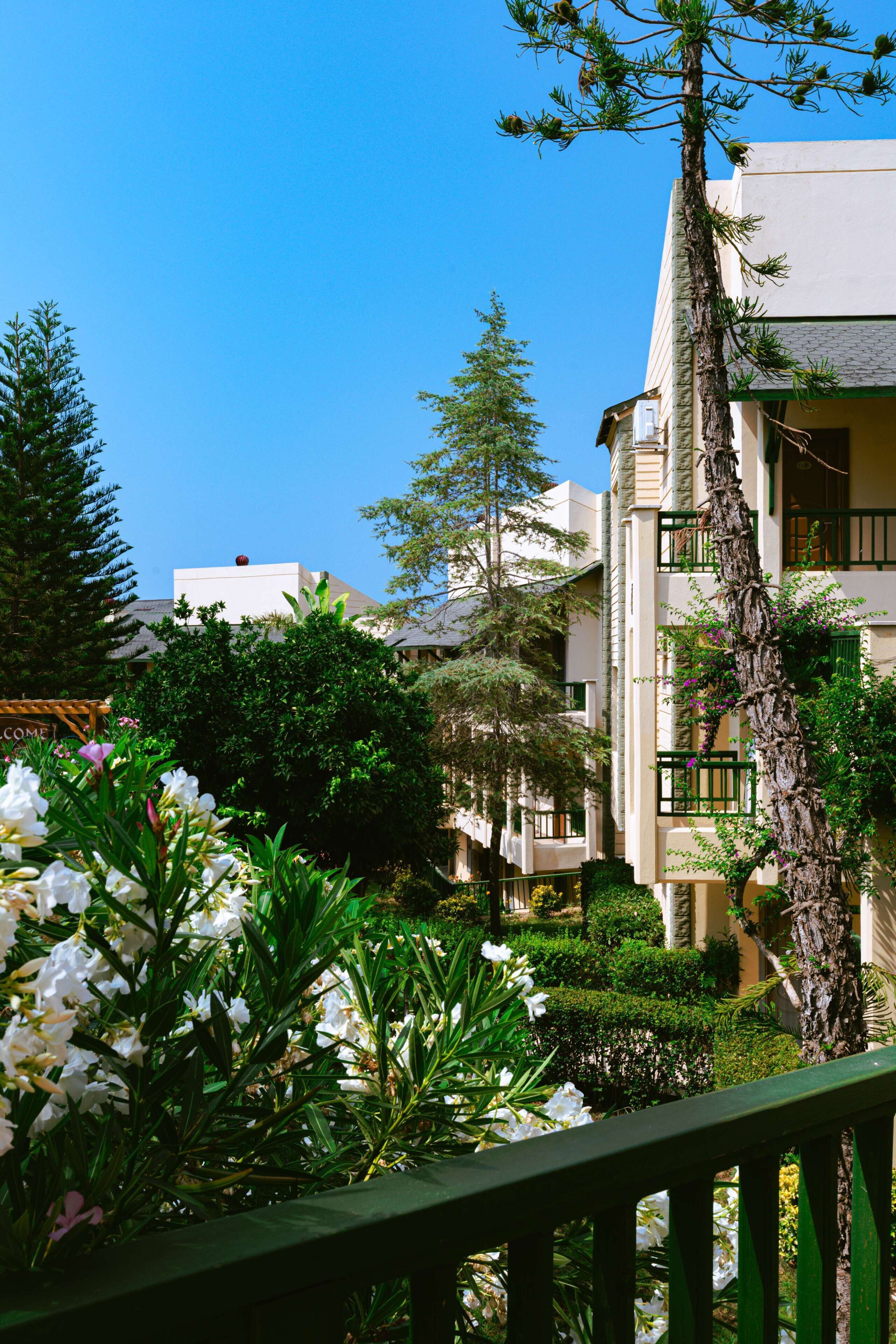 Ein Gebäude mit einem Balkon, umgeben von Grünpflanzen und Blumen.
