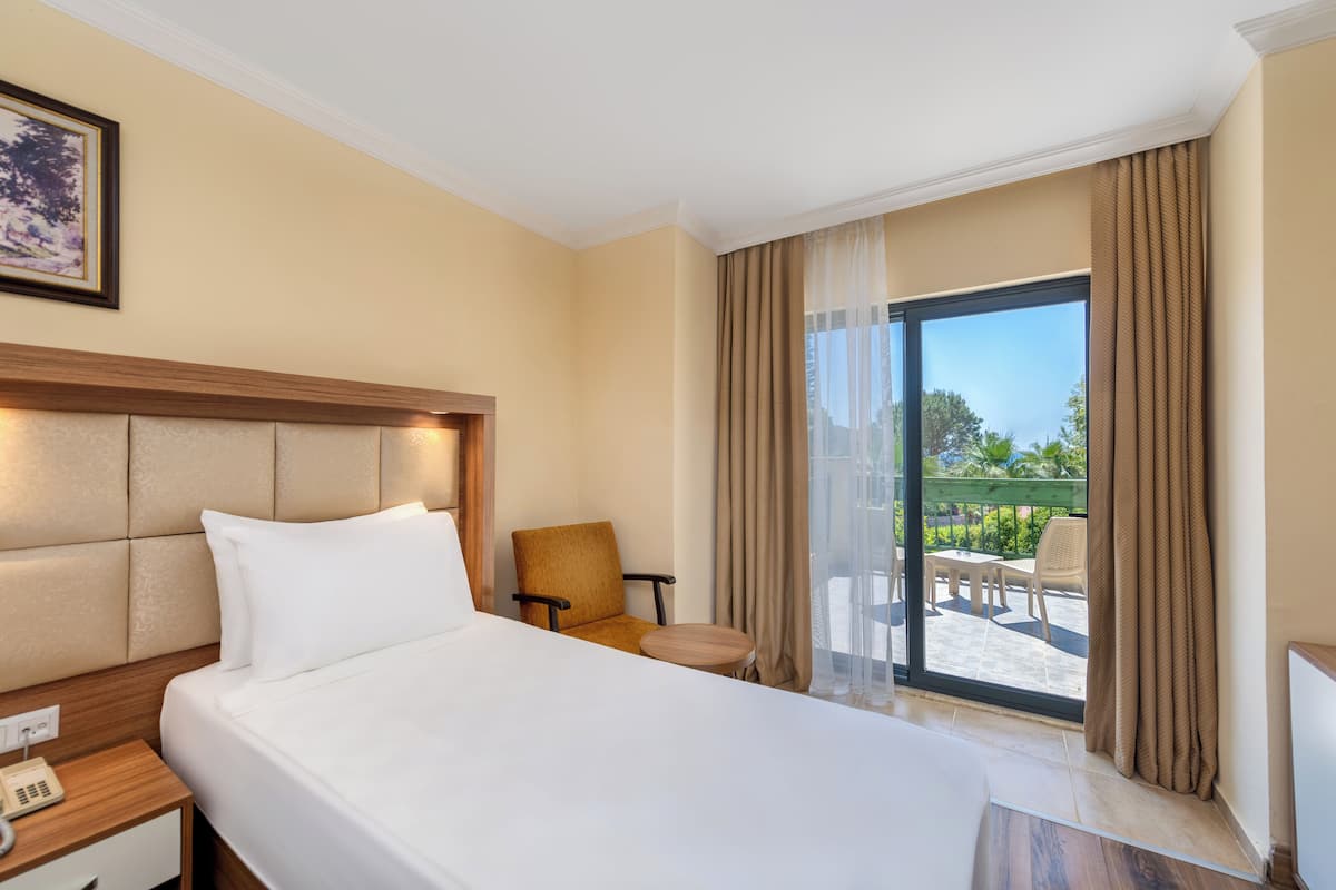 Ein Hotelzimmer mit einem großen Bett, einem Sessel, einem kleinen Tisch und einem Balkon mit Sitzgelegenheit.