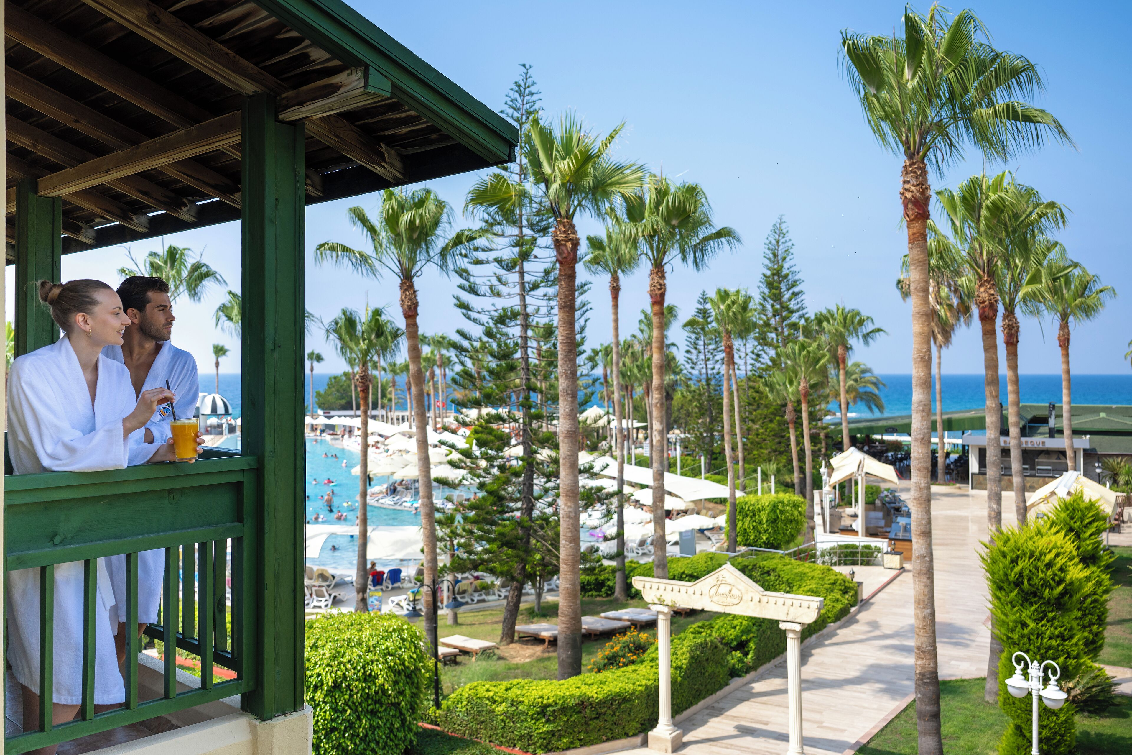 A resort with a pool, palm trees, and a covered area with two people.