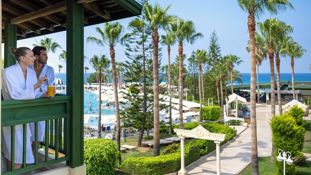 Resort com piscina, palmeiras e área coberta com duas pessoas.