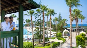 A resort with a pool, palm trees, and a covered area with two people.