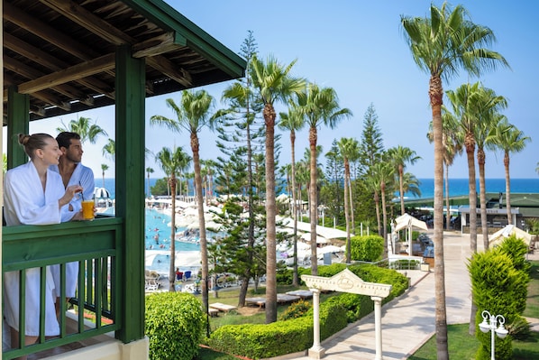 Un resort con piscina, palmeras y una zona cubierta con dos personas.