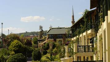A hotel with a green roof, multiple balconies, and a garden area with various plants and a pathway.