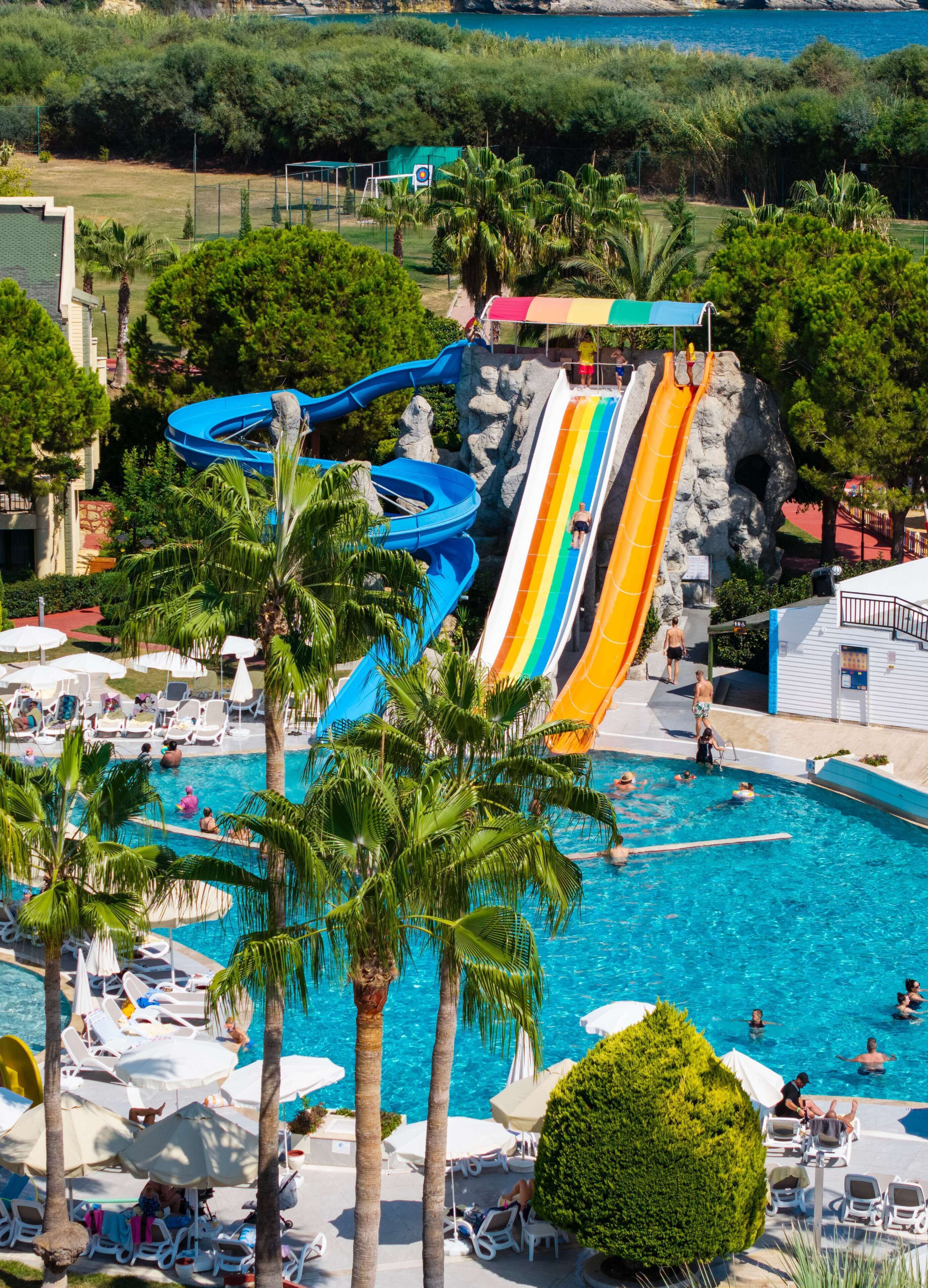 A water park with multiple slides and a swimming pool area with sun loungers and umbrellas.