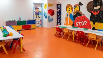 A children's art studio with colorful furniture and LEGO figures on the walls.