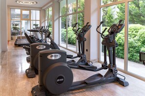 A gym with exercise equipment, large windows, and a view of greenery. - Oz Hotels Side Premium (Manavgat)
